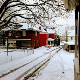 A tranquil winter scene featuring snow-covered houses and bare tree branches.