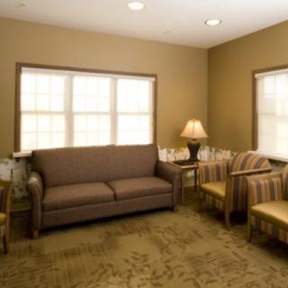 A cozy living room with a sofa, chairs, and a lamp by the window.