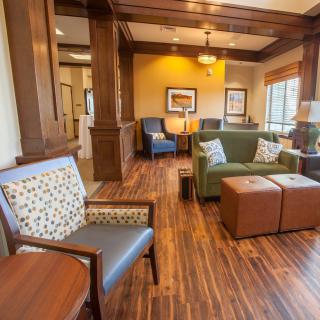 A cozy lounge area with wooden flooring, comfortable chairs, and a sofa.