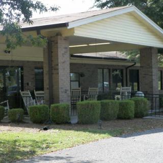 A cozy building with a welcoming front porch and outdoor seating surrounded by well-maintained greenery.