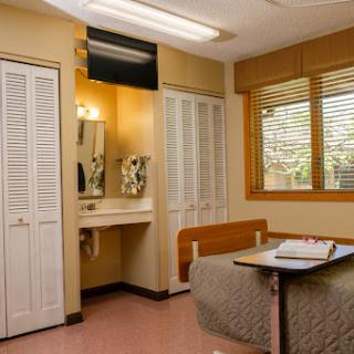 A view of a hospital room interior, featuring a bench and a vanity area with a mirror.