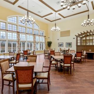 A spacious and elegant dining hall with large windows, wooden floors, and decorative chandeliers.