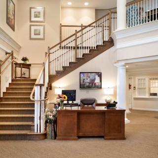 Modern lobby with a wooden staircase and reception desk.