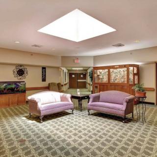 A cozy lobby area featuring two sofas, a patterned carpet, and a skylight.