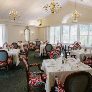 An elegantly designed restaurant dining room with set tables and chandeliers.
