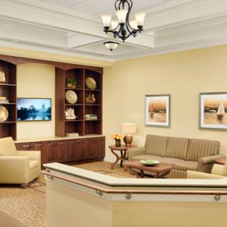 A cozy and modern waiting room featuring comfortable seating, decorative shelves, and soft lighting.