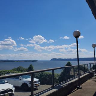 A serene view overlooking the water on a clear day, with clouds scattered across the blue sky.