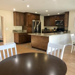 A modern kitchen with wooden cabinets and stainless steel appliances, featuring an open layout with a dining area.