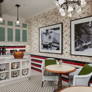 A vintage-style kitchen with black and white photos, cozy seating, and patterned flooring.