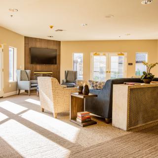 A sunlit living room with comfortable seating and a large television.