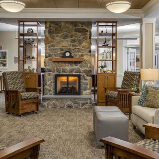 A cozy living room featuring a stone fireplace, comfortable seating, and warm lighting.