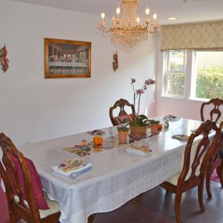 A well-decorated dining room featuring a chandelier, wooden chairs, and a table set with various items.
