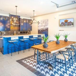 A modern kitchen and dining area featuring blue cabinets, a wooden table, and stylish pendant lights.