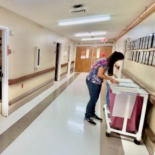 A healthcare staff member organizing or retrieving items from a cart in a hospital hallway.