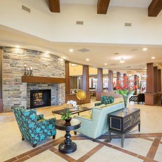 A spacious and elegantly decorated lobby area featuring a modern fireplace, comfortable seating, and bright lighting.