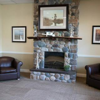 A cozy lounge area featuring a stone fireplace with artwork above and leather chairs on either side.