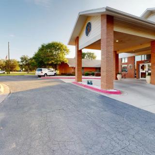 Entrance of a building with a driveway and parking area.