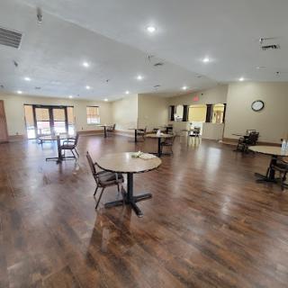 A spacious dining area featuring multiple tables and chairs, illuminated by bright lights.