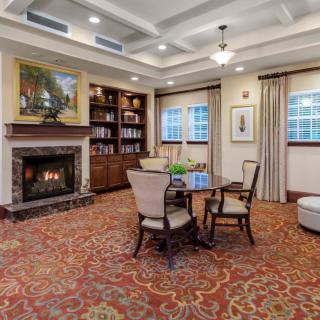A cozy living room featuring a fireplace, bookshelves, and a seating area with a table and chairs.