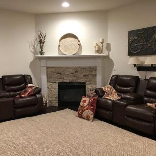 A cozy living room featuring a fireplace, two leather sofas, and decorative elements.
