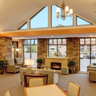 A cozy living room with a fireplace, large windows, and comfortable furniture.