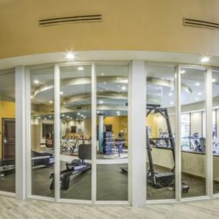 A modern gym with large glass walls showcasing various exercise equipment and treadmills.