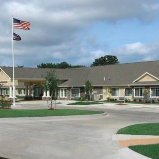 Retirement home with flags flying outside under a cloudy sky.