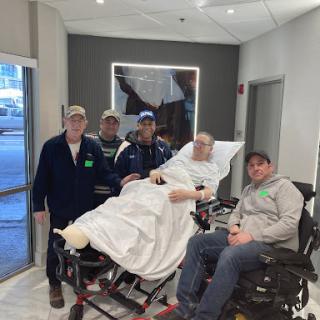 A group of caregivers posing for a photo with a patient in a hospital setting.