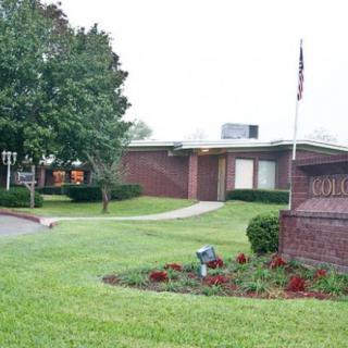 A brick building surrounded by a well-maintained lawn with trees and a flagpole.
