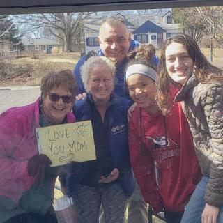 A joyful gathering of friends and family, holding a sign and sharing smiles.