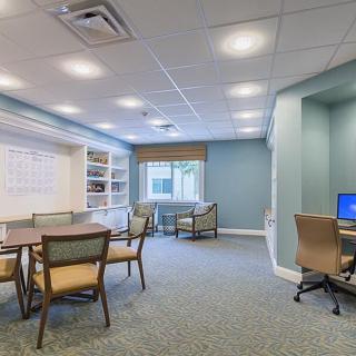 A modern office meeting room with tables, chairs, and a computer station.