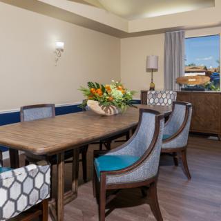 A modern dining room with an elegant table, cushioned chairs, and a floral centerpiece.
