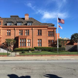A large brick building with American flags flying in front, set against a clear blue sky.