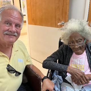 A heartwarming moment shared between a caregiver and an elderly woman in a wheelchair.