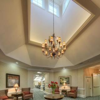 A spacious lobby with a grand chandelier and comfortable seating area beneath a skylight.