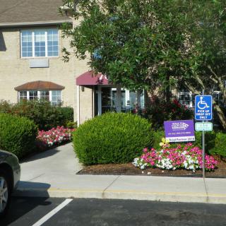 Entrance to a building with landscaped flowers and a designated parking space.