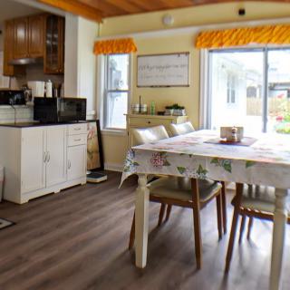 A cozy kitchen and dining area with a table, chairs, and large windows letting in natural light.
