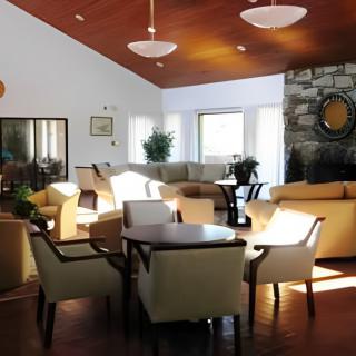 A cozy living room with comfortable seating, featuring a stone fireplace and ample natural light.