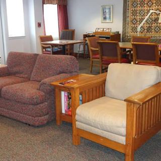 A cozy living room featuring a couch, armchair, and table with carpeted flooring.