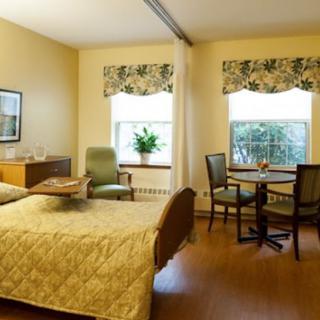 A cozy bedroom with a bed, seating area, and table by the window.