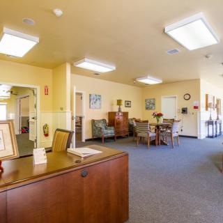 A view of a spacious office reception area with desks, chairs, and decor under bright indoor lighting.