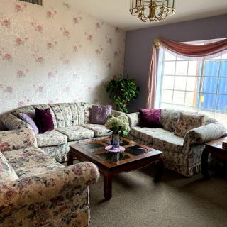 A cozy living room featuring floral patterned sofas and a bright window.