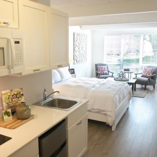A modern studio apartment with an integrated kitchen and bedroom area, featuring bright decor and cozy furnishings.