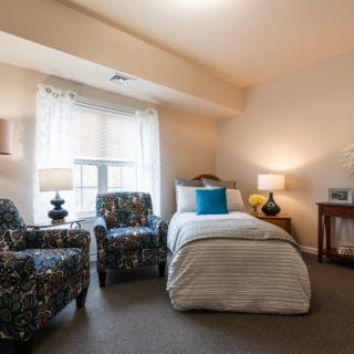Cozy bedroom with a single bed and armchairs by the window.
