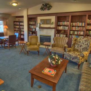 A cozy library with comfortable seating and a fireplace surrounded by bookshelves.