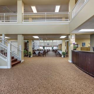 A spacious lobby with carpeted flooring, a reception desk, and an open area leading to a seating arrangement.
