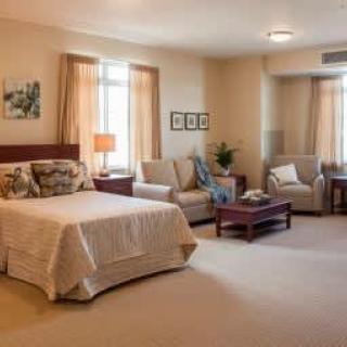 A spacious, well-lit bedroom featuring a large bed, comfortable sofa seating, and tasteful decor.