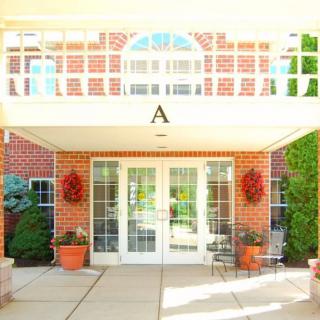 A welcoming brick building entrance with potted plants and glass doors.