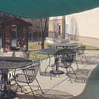 An outdoor patio area with tables and chairs under shade.