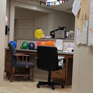 A cozy office workspace decorated with colorful balloons and a neat desk setup.